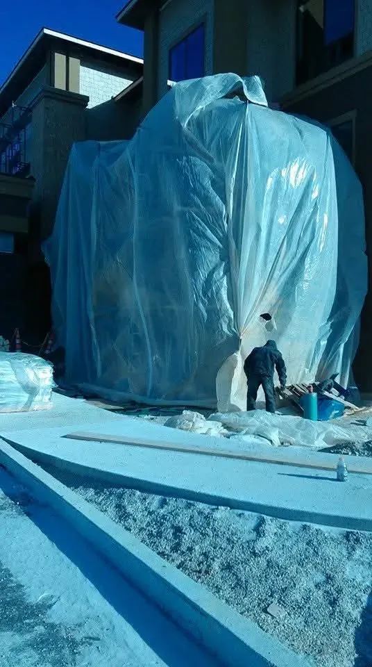 Work area on the Indiana hotel project tented in plastic sheeting for cold-weather stonework, with a worker at the opening