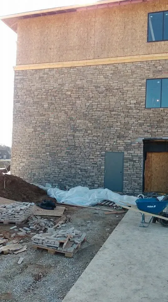 Full-height ledge stone wall completed on one building of the Indiana hotel project, with pallets of stone in front