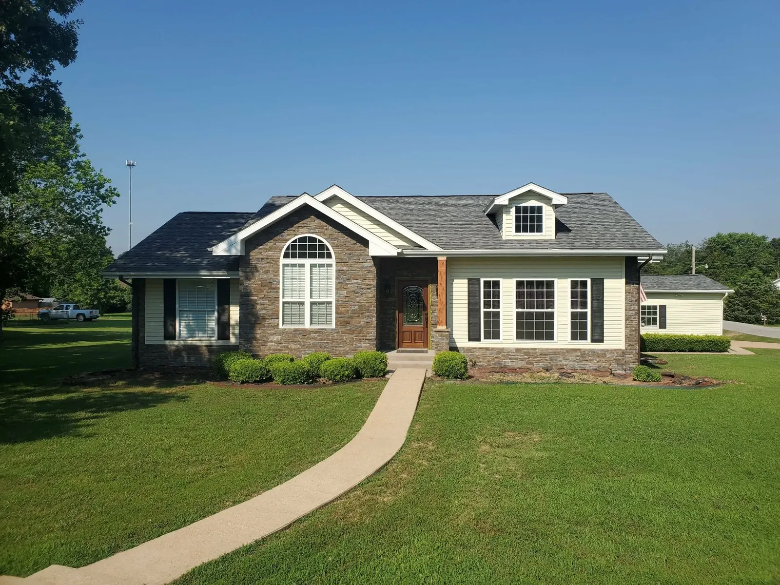 House front with a stone gable and arched window, stone entry surround and stone wainscot