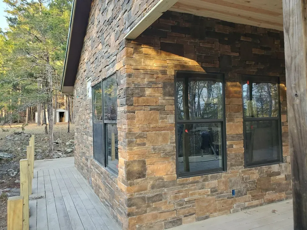 House corner wrapped in Walnut Ridge and gray ledge stone beside a deck