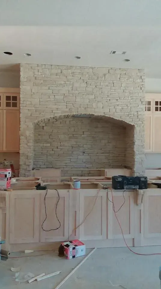 Kitchen range alcove clad in light cream stone, cabinets still unfinished during the build
