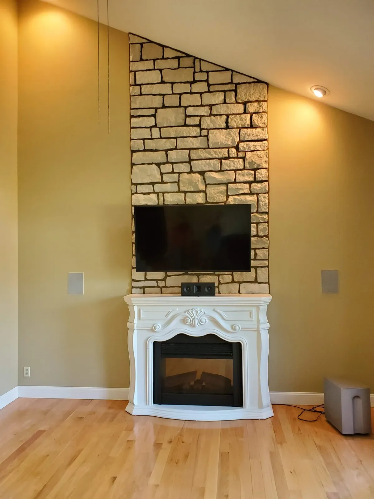 Limestone accent wall behind a television lit by ceiling spotlights