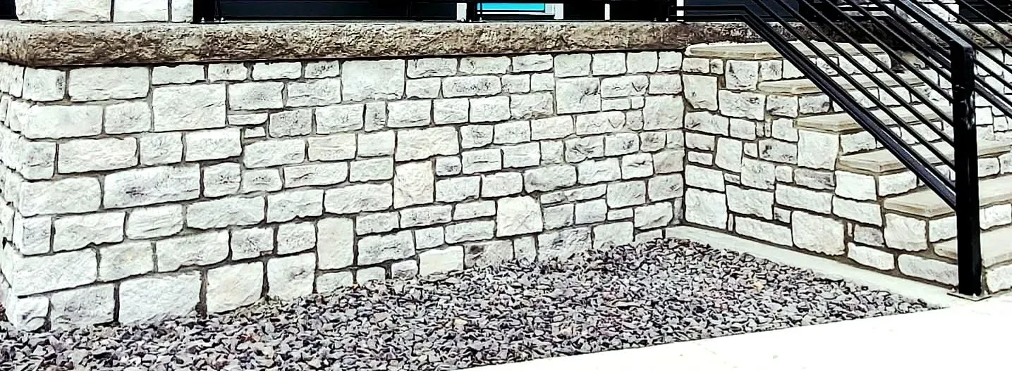 Limestone porch retaining wall with a stone cap course beside steps