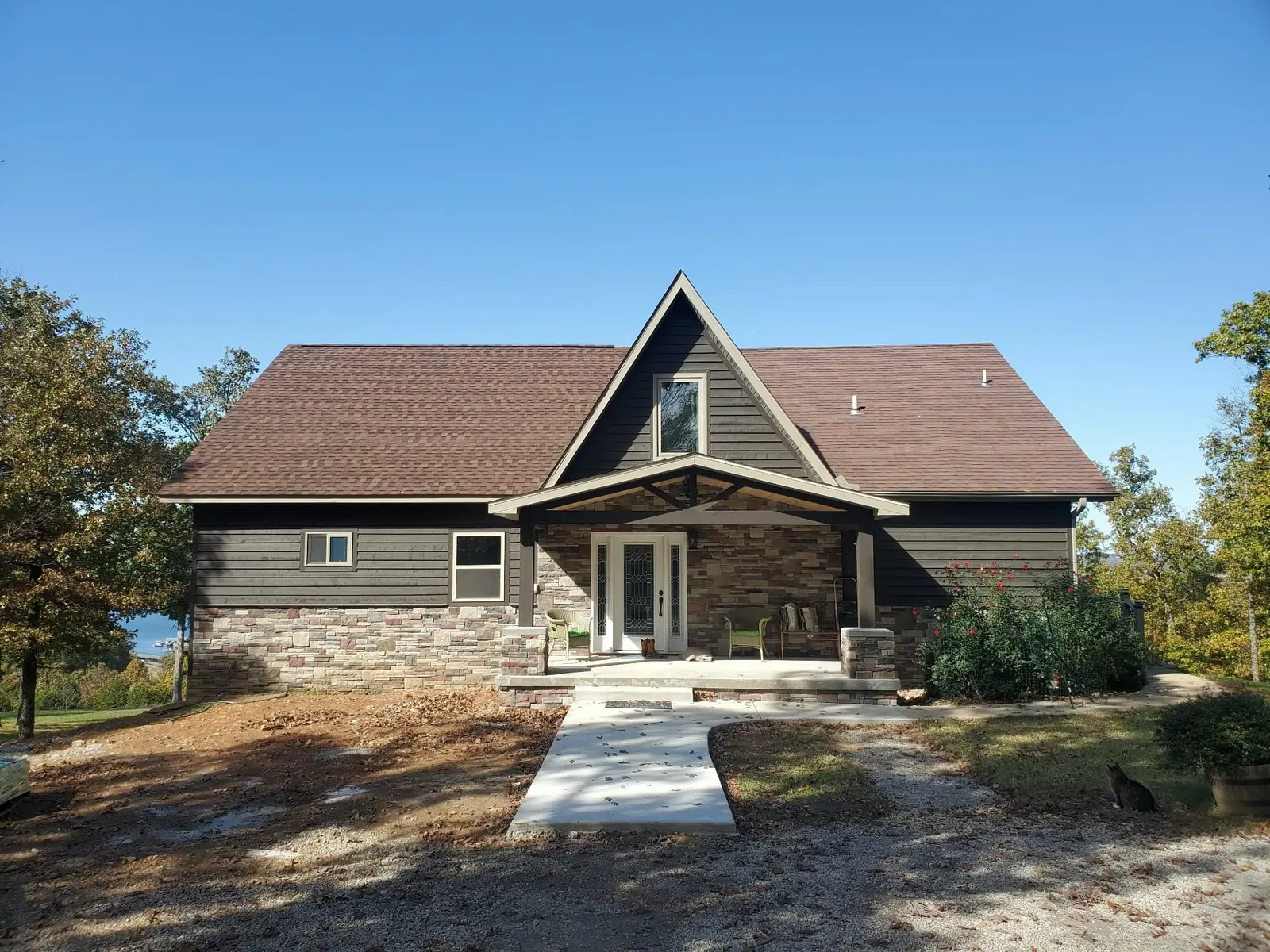 Front view of a house with a stone entry porch and stone wainscot in a multi-color mix under dark siding