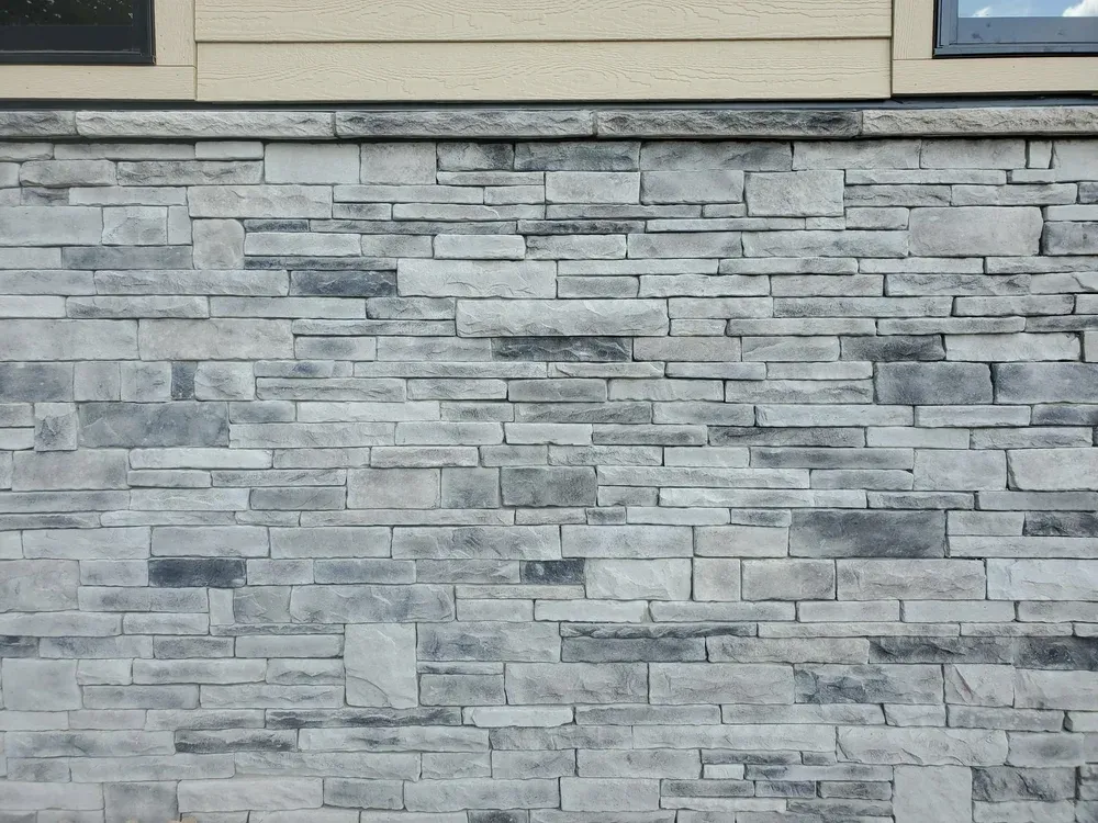 European Drystack veneer in Ozark Gray below beige siding, finished with a cap course