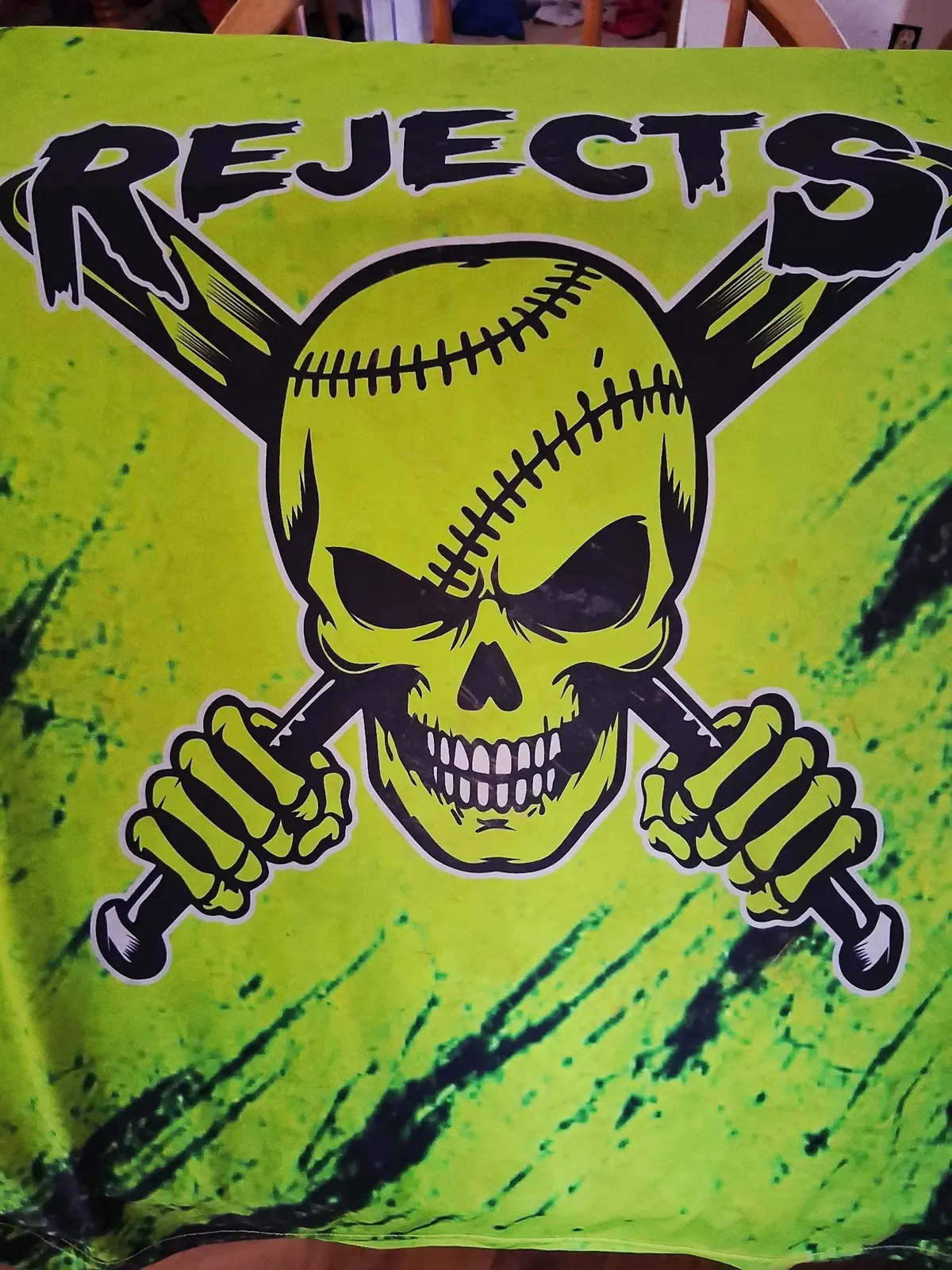 Front of the Rejects ball team jersey in neon green, with the team name over a skull holding crossed baseball bats